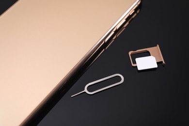 Photo of SIM card, smartphone and ejector on black background, above view
