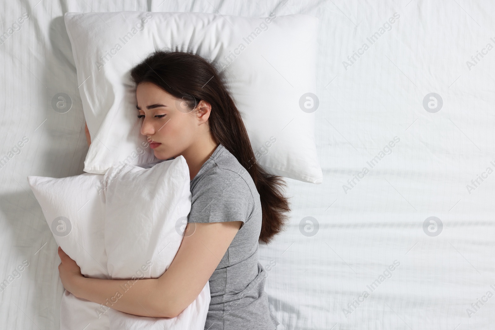 Photo of Young woman suffering from insomnia on bed, top view. Space for text