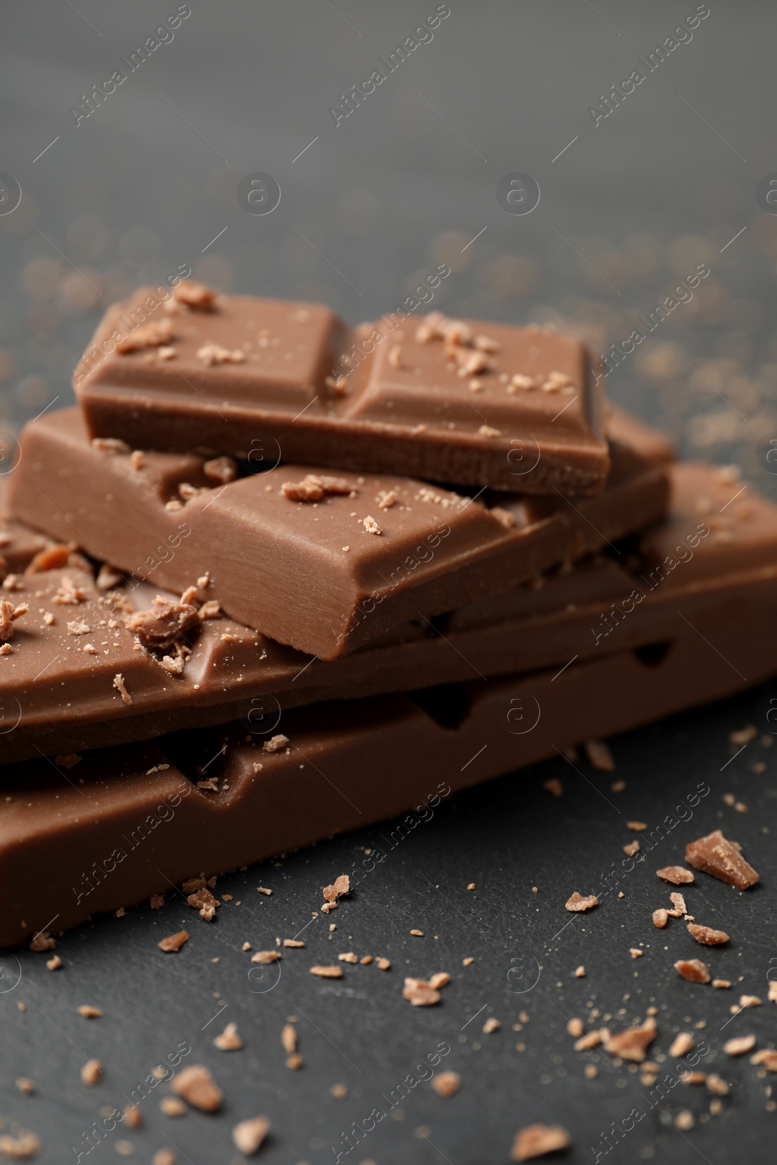 Photo of Pieces of tasty chocolate on grey table, closeup