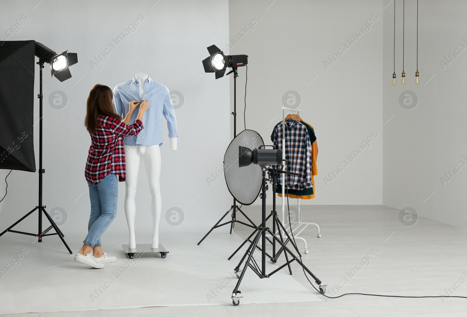 Photo of Woman putting clothes on ghost mannequin in professional photo studio