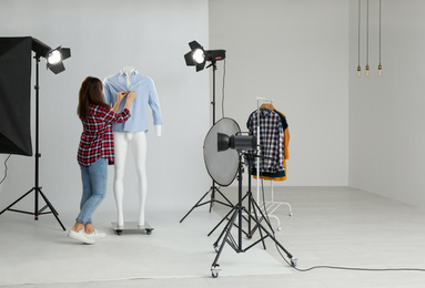 Woman putting clothes on ghost mannequin in professional photo studio