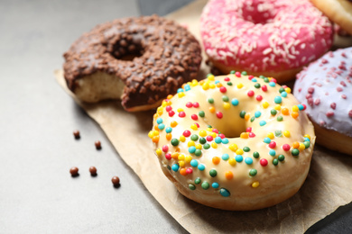 Photo of Delicious glazed donuts on grey table, closeup