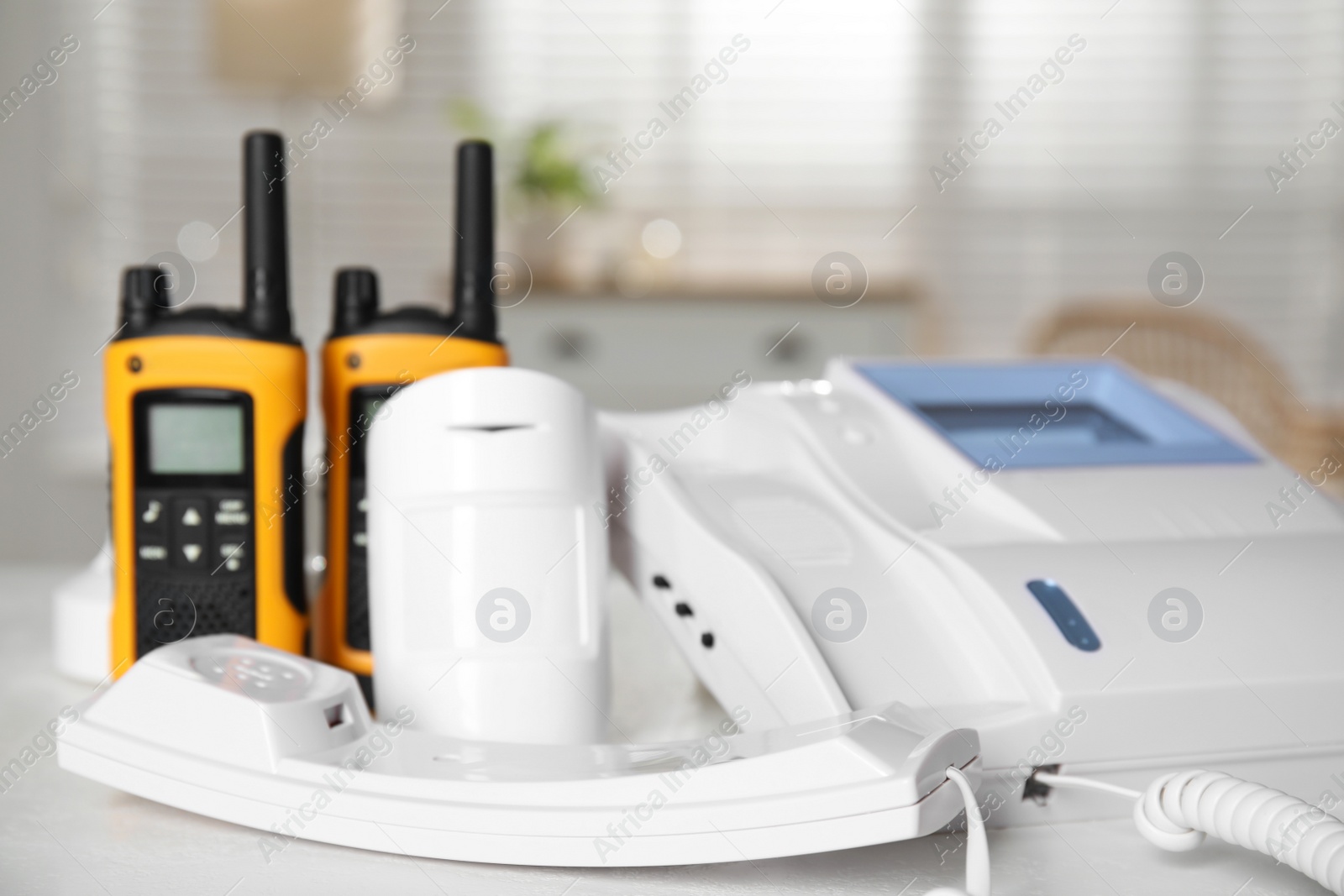 Photo of Intercom, movement detector and walkie talkies on white table indoors, closeup. Home security system