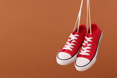 Pair of red classic old school sneakers on brown background. Space for text