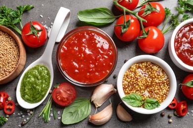 Flat lay composition with different sauces and ingredients on gray background