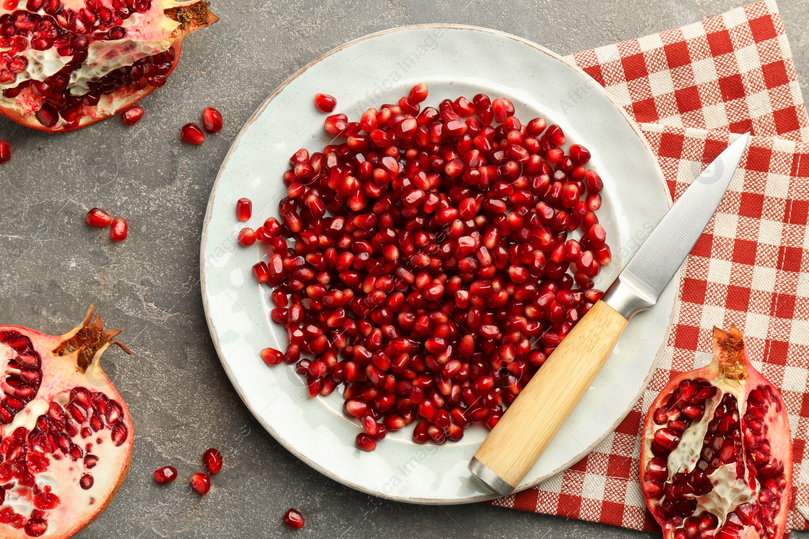 Photo of Tasty ripe pomegranate and grains on grey table, flat lay