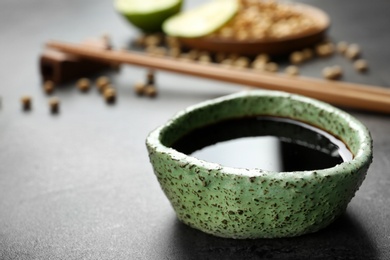 Bowl of soy sauce on grey table, closeup. Space for text