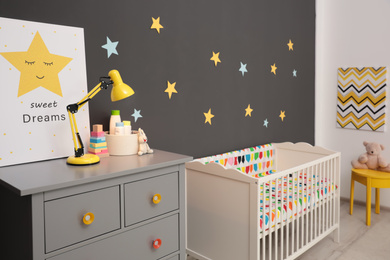 Photo of Cute baby room interior with modern crib near stars on wall