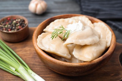 Photo of Bowl of tasty cooked dumplings on board, closeup