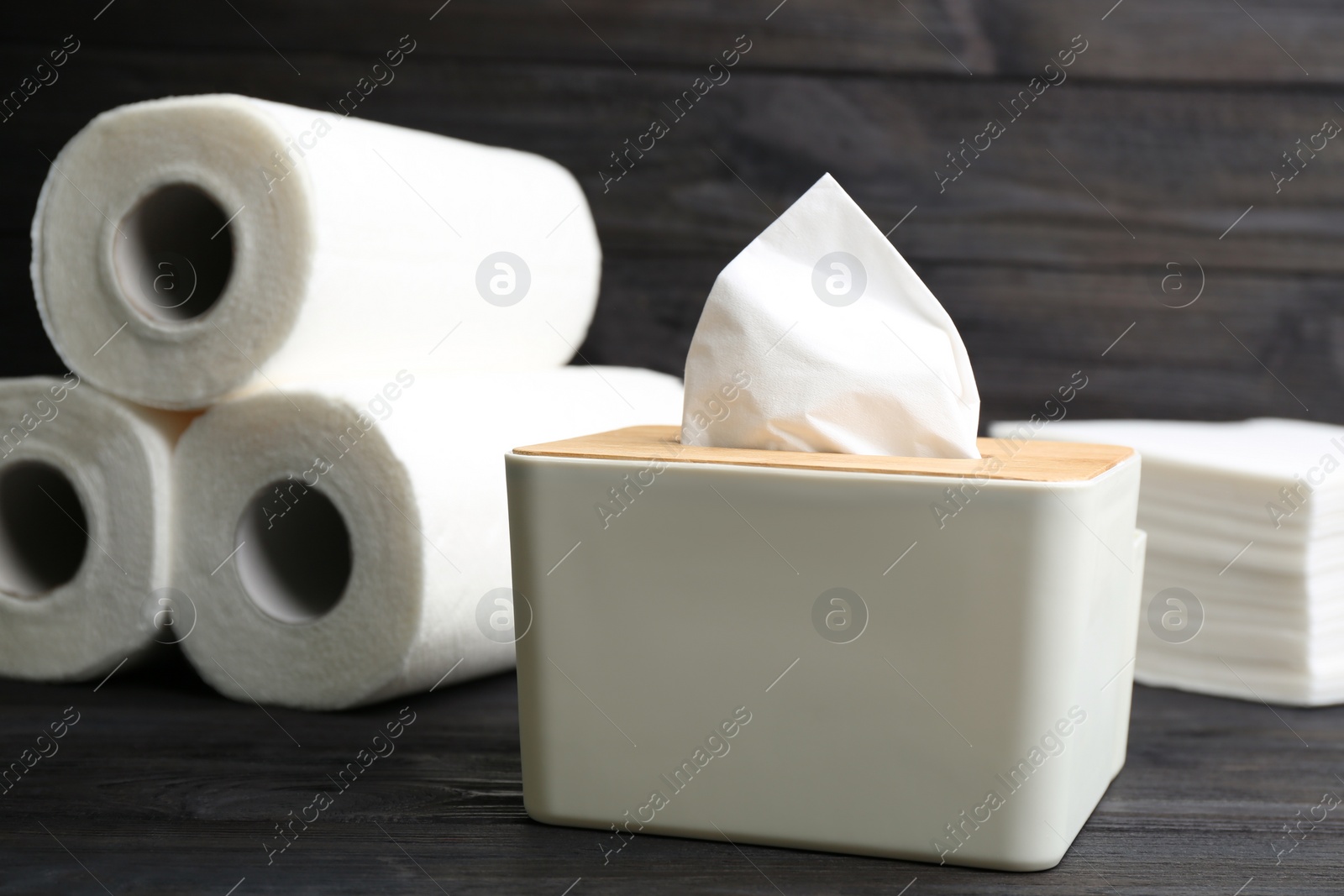 Photo of Tissues and rolls of paper towels on wooden table