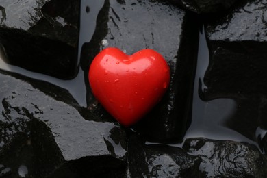 Photo of Red decorative heart on stones and water, closeup