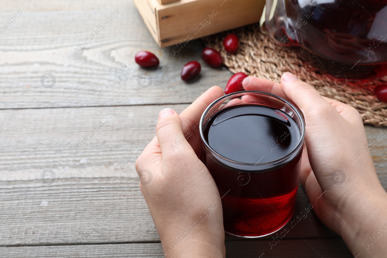 Photo of Woman with cup of fresh dogwood tea at wooden table, closeup. Space for text