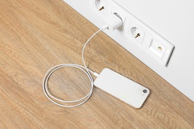 Modern mobile phone charging on wooden table