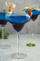 Tasty cocktail decorated with physalis fruits on grey table