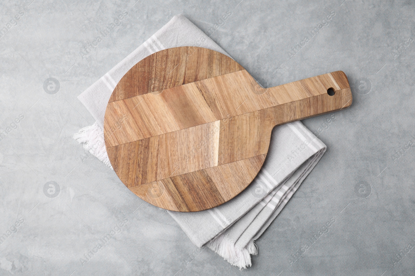 Photo of One wooden cutting board on light grey table, top view. Cooking utensil