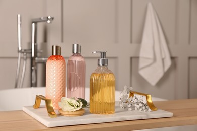 Photo of Liquid soap and other toiletries on wooden table in bathroom