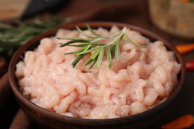 Photo of Fresh raw minced meat and rosemary in bowl on table, closeup