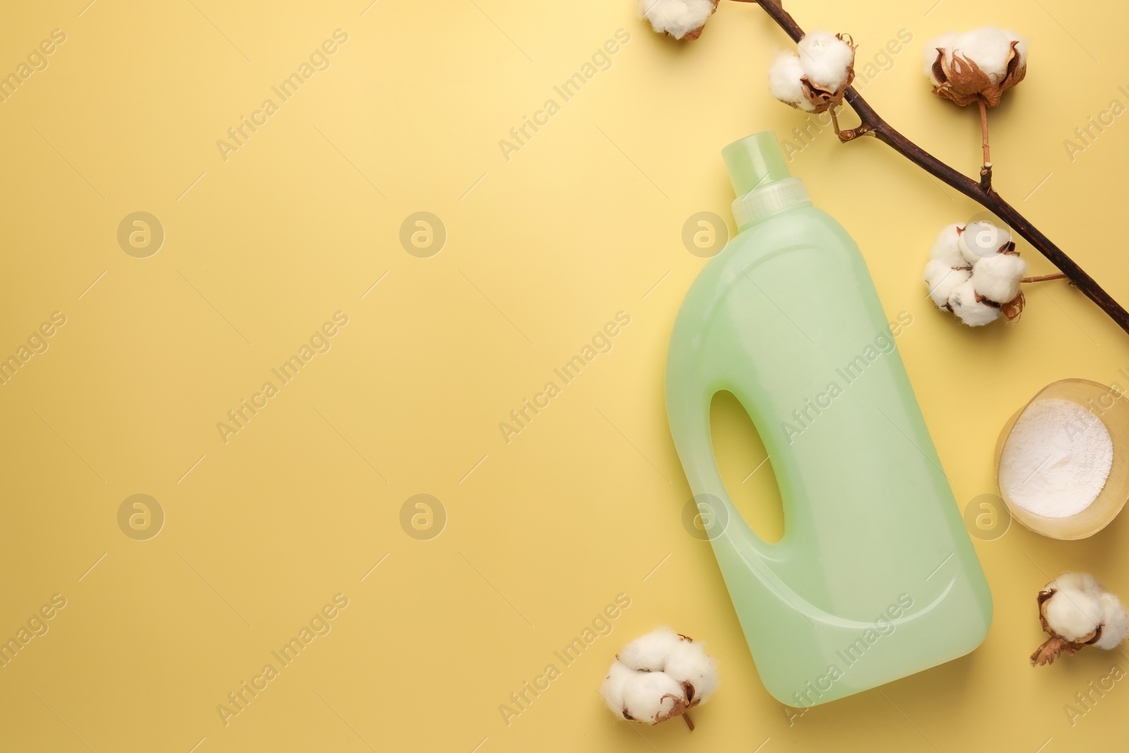 Bottle of fabric softener, detergent powder and cotton flowers on pale yellow background, flat lay. Space for text Photo of Bottle of fabric softener, detergent powder and cotton flowers on pale yellow background, flat lay. Space for text