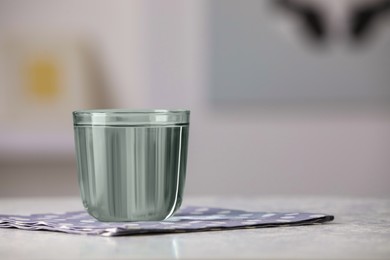 Glass of pure water on white table indoors, space for text