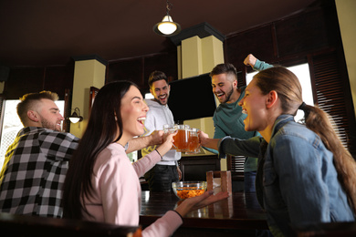 Photo of Group of friends celebrating victory of favorite football team in sport bar