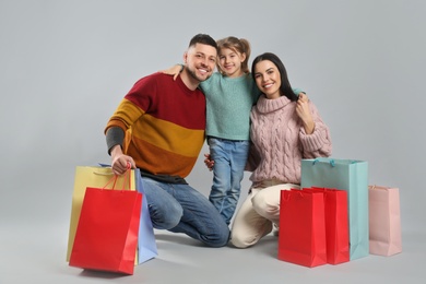 Photo of Happy family with paper bags on grey background. Christmas shopping