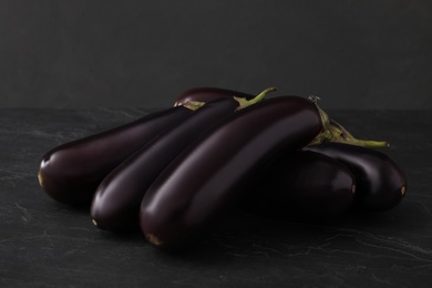 Pile of raw ripe eggplants on black table