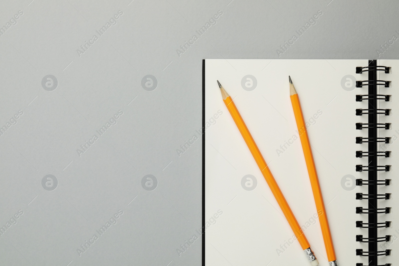 Photo of Notebook and pencils on gray background, top view. Space for text