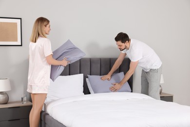 Couple changing bed linens in room. Domestic chores