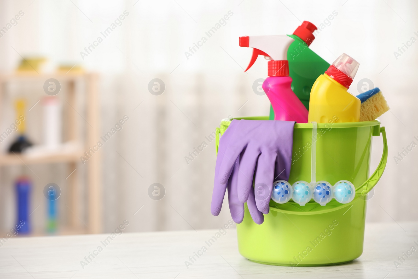 Photo of Different toilet cleaning supplies and tools in bucket on table indoors, space for text