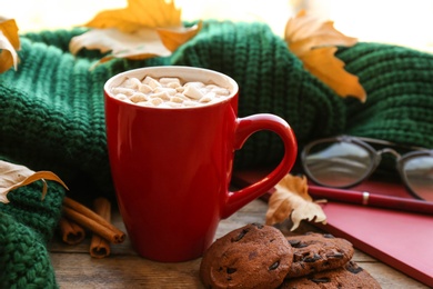 Composition with cup of hot drink, sweater and autumn leaves on windowsill. Cozy atmosphere