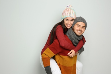 Young happy couple in warm clothes on light background. Christmas celebration