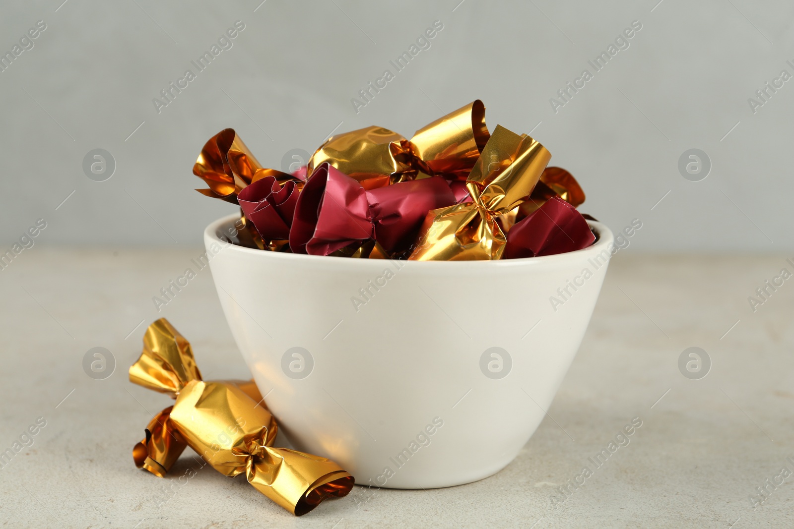 Photo of Candies in colorful wrappers on light beige table, closeup