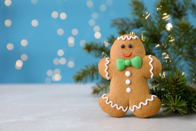 Photo of Gingerbread man and fir branches light grey marble table, closeup. Space for text