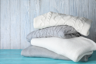 Image of Stack of folded warm sweaters on turquoise wooden table 