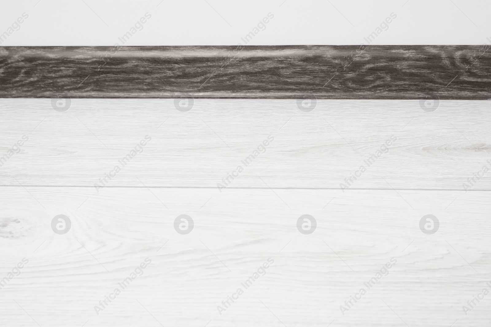 Photo of Black wooden plinth on laminated floor near white wall indoors