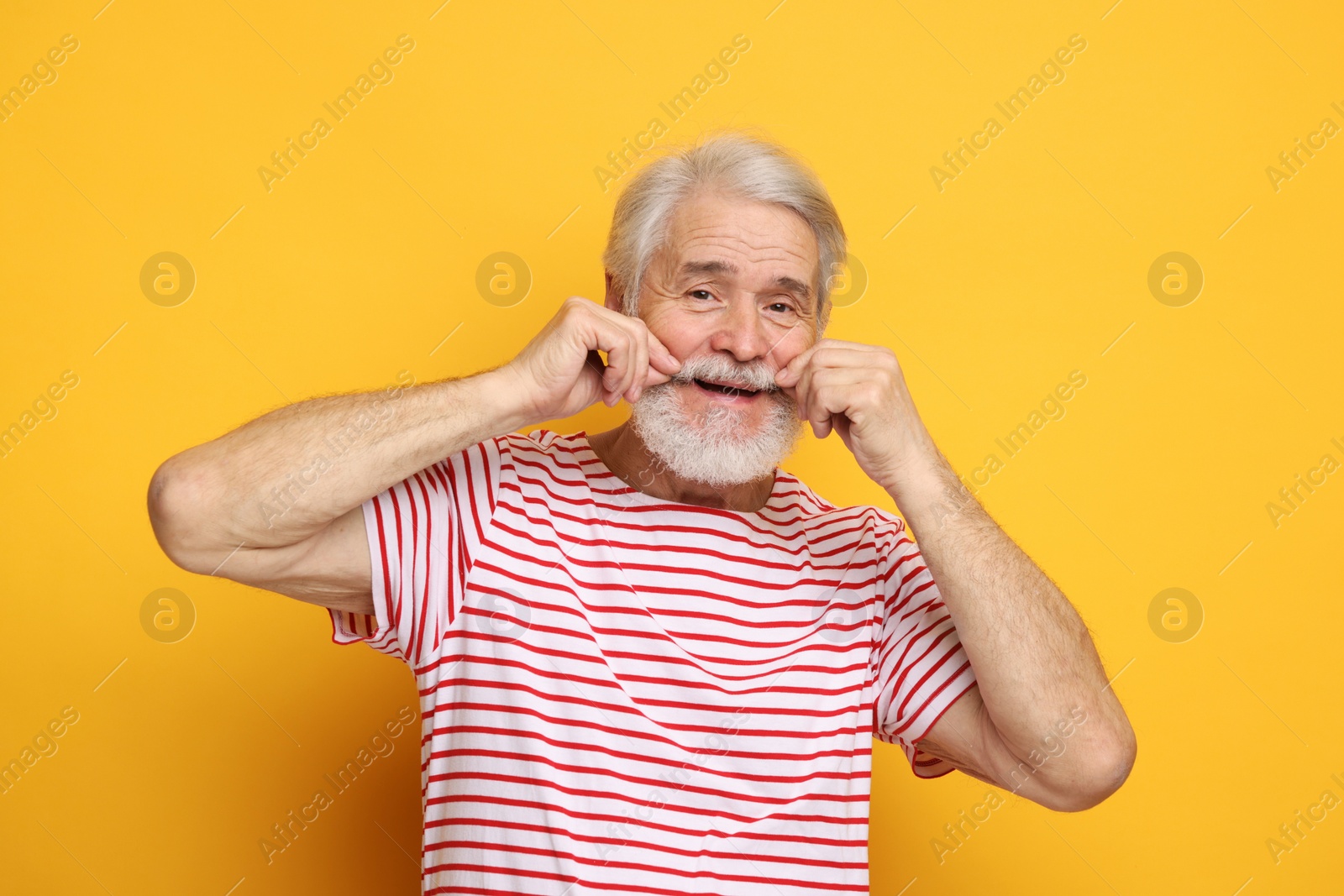 Photo of Senior man touching mustache on orange background