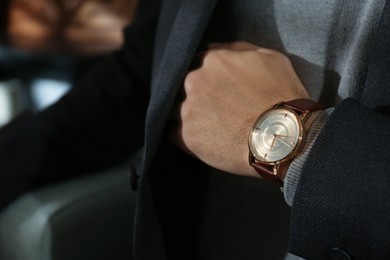 Photo of Man with luxury wrist watch on blurred background, closeup. Space for text