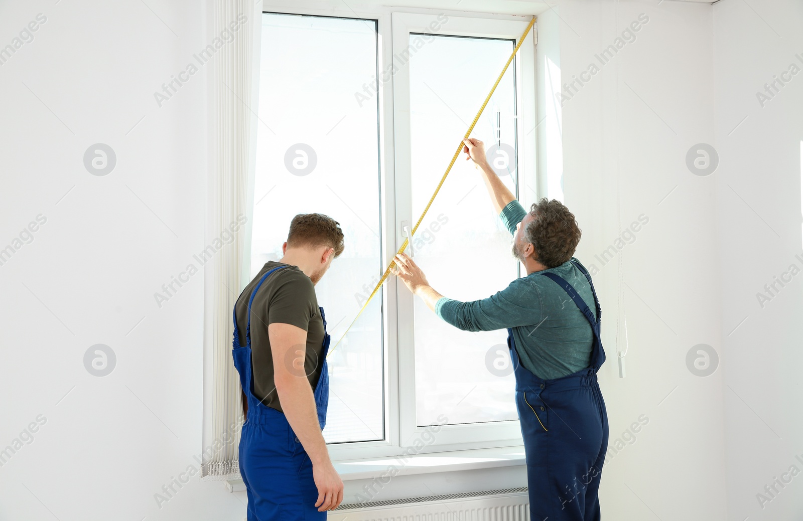 Photo of Service men measuring window for installation indoors