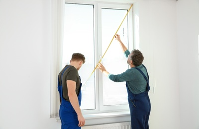 Photo of Service men measuring window for installation indoors