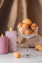 Photo of Delicious nut shaped cookies and burning candles on white table