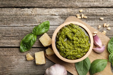 Photo of Tasty pesto sauce, basil, pine nuts, cheese and garlic on wooden table, top view