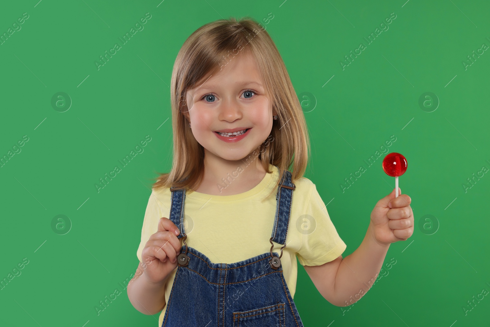 Photo of Portrait of happy girl with lollipop on green background