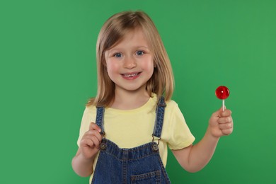 Portrait of happy girl with lollipop on green background