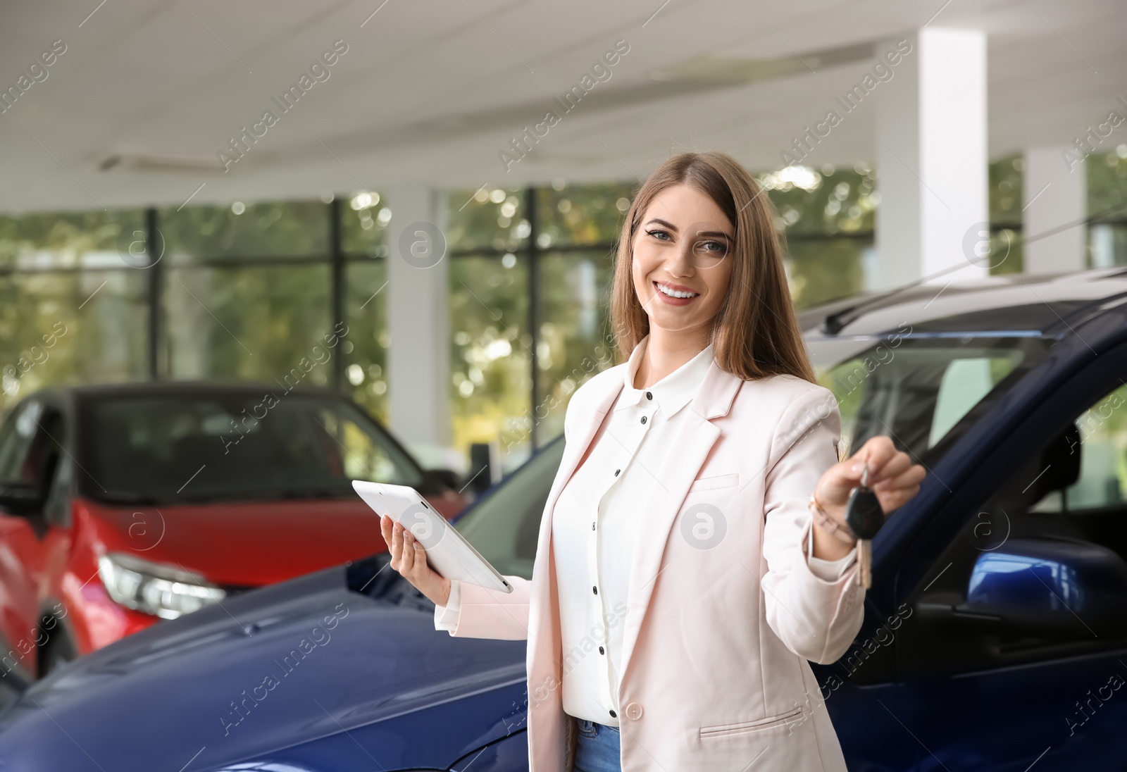 Photo of Woman with tablet and car keys in modern auto dealership