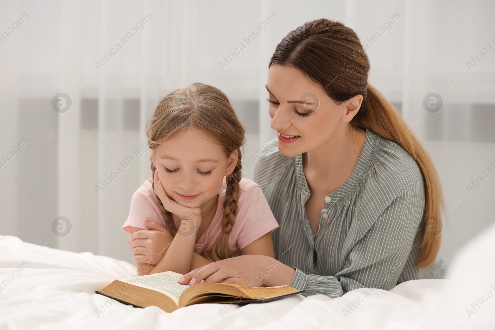 Photo of Girl and her godparent reading Bible together at home