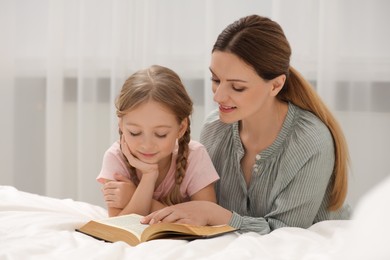 Girl and her godparent reading Bible together at home