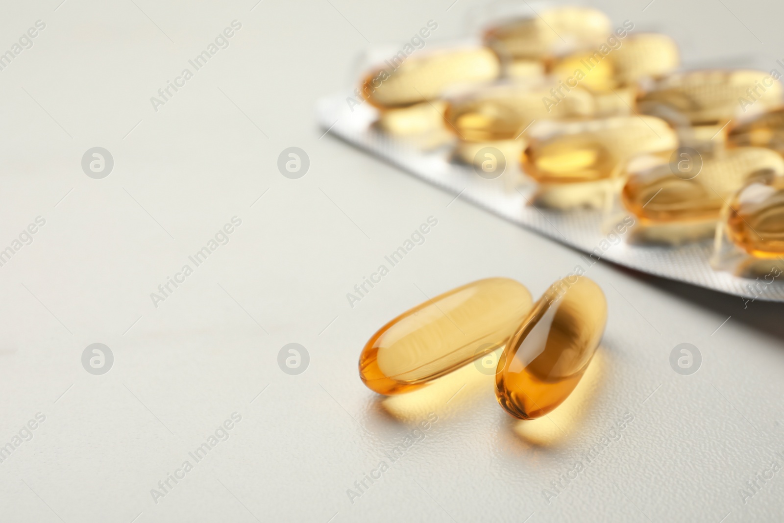 Photo of Dietary supplement capsules on white table, closeup. Space for text