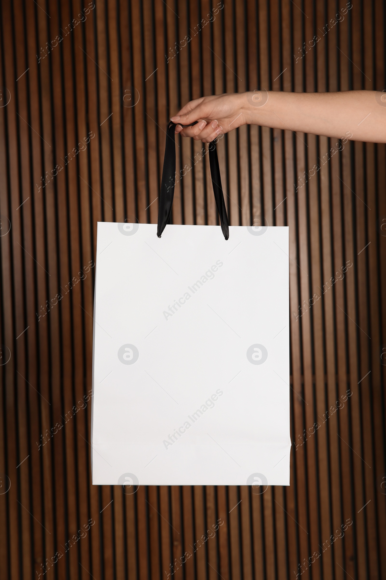 Photo of Woman holding paper shopping bag on wooden background. Mock up for design