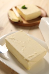 Photo of Block of tasty butter on wooden table, closeup