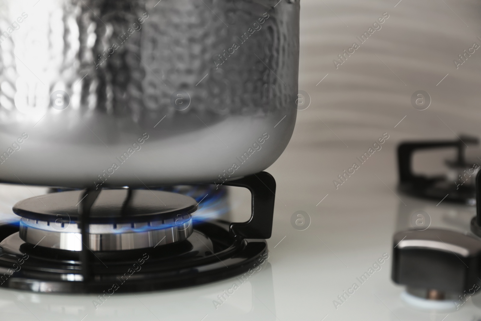 Photo of Shiny steel saucepan on modern gas stove, closeup. Space for text